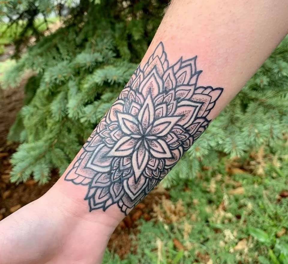 Geometric dotwork mandala tattoo across a wrist and forearm