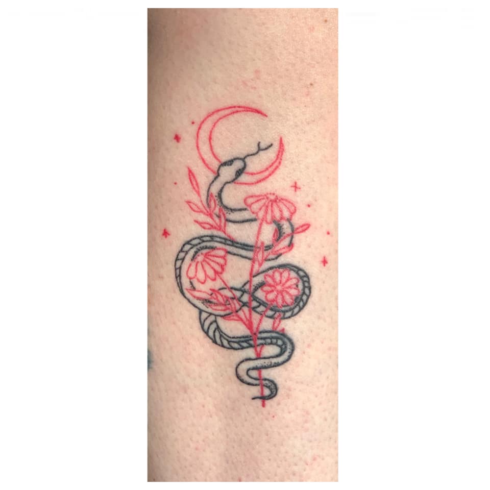 Fine-line black snake tattoo winding through daisies and a red moon