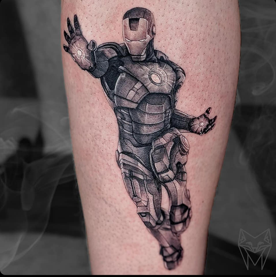 Black and grey Iron Man tattoo in flight, on a lower leg