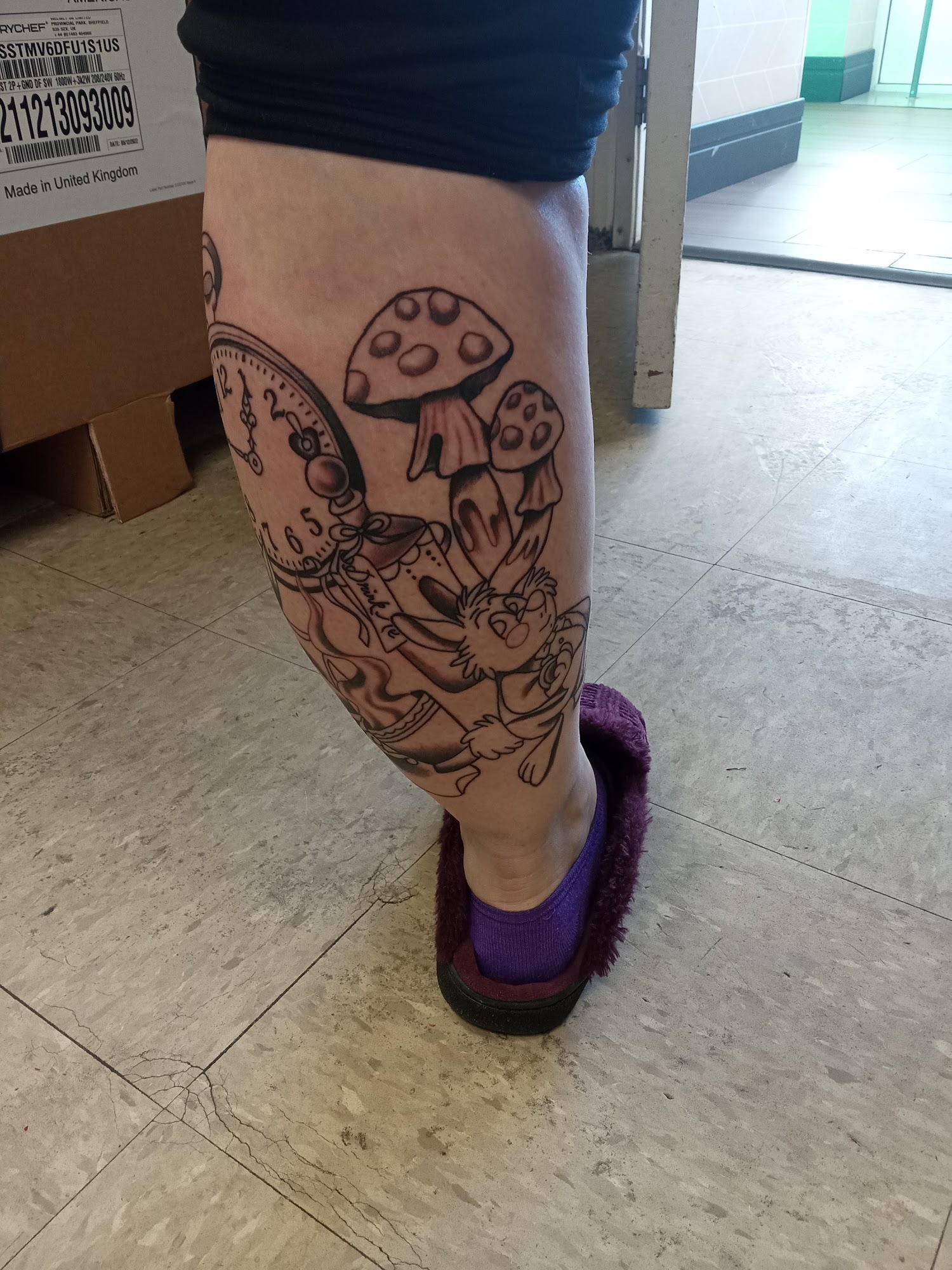 Black and grey Alice in Wonderland white rabbit tattoo with a pocket watch and mushrooms, on a calf